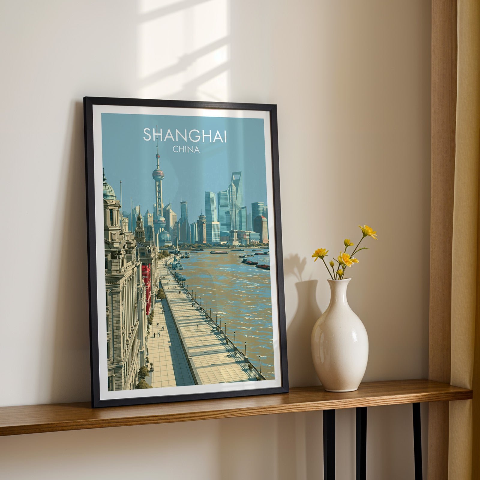 Black framed Shanghai China print on a narrow hallway console in sunlight, styled with yellow flowers