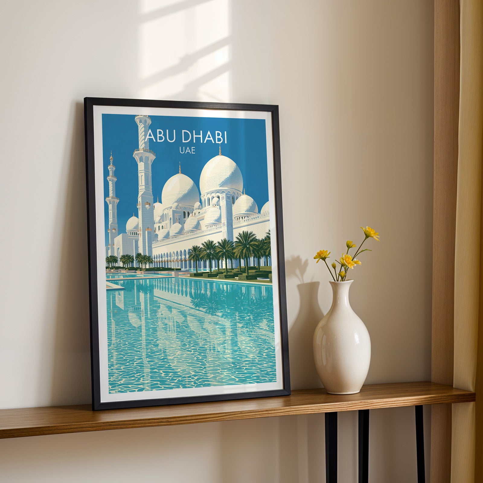 Black framed Sheikh Zayed Mosque Abu Dhabi print on a narrow hallway console in sunlight, styled with yellow flowers