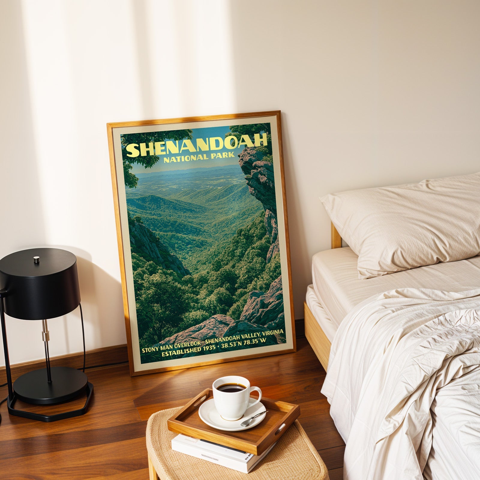 Stony Man Overlook print in a gold frame on the floor beside a made bed and a black table lamp