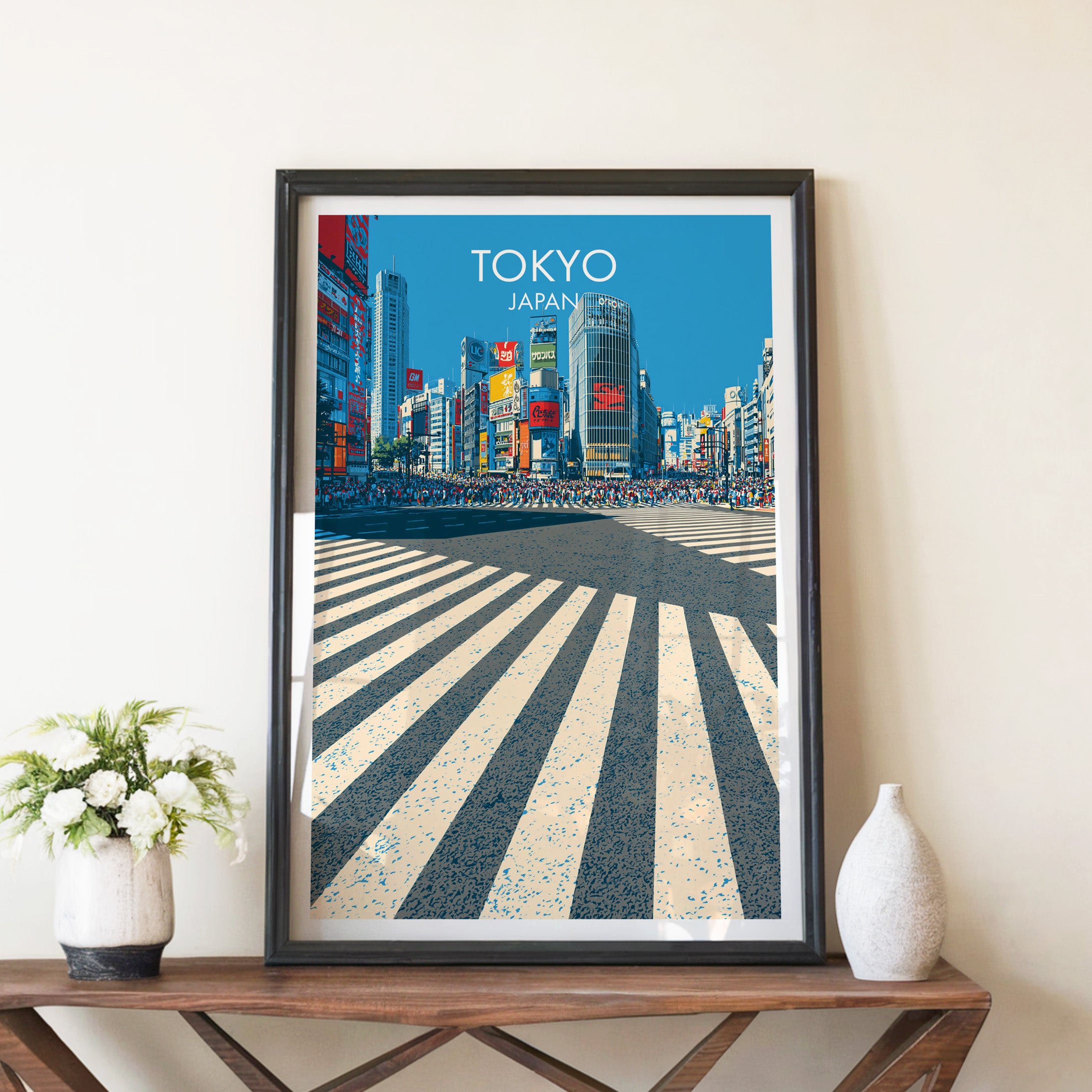 Shibuya Crossing Tokyo Japan travel poster in a black frame on a wooden console table with white flowers