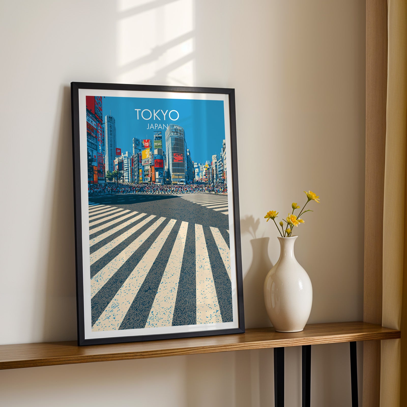 Black framed Shibuya Crossing Tokyo Japan print on a narrow hallway console in sunlight, styled with yellow flowers