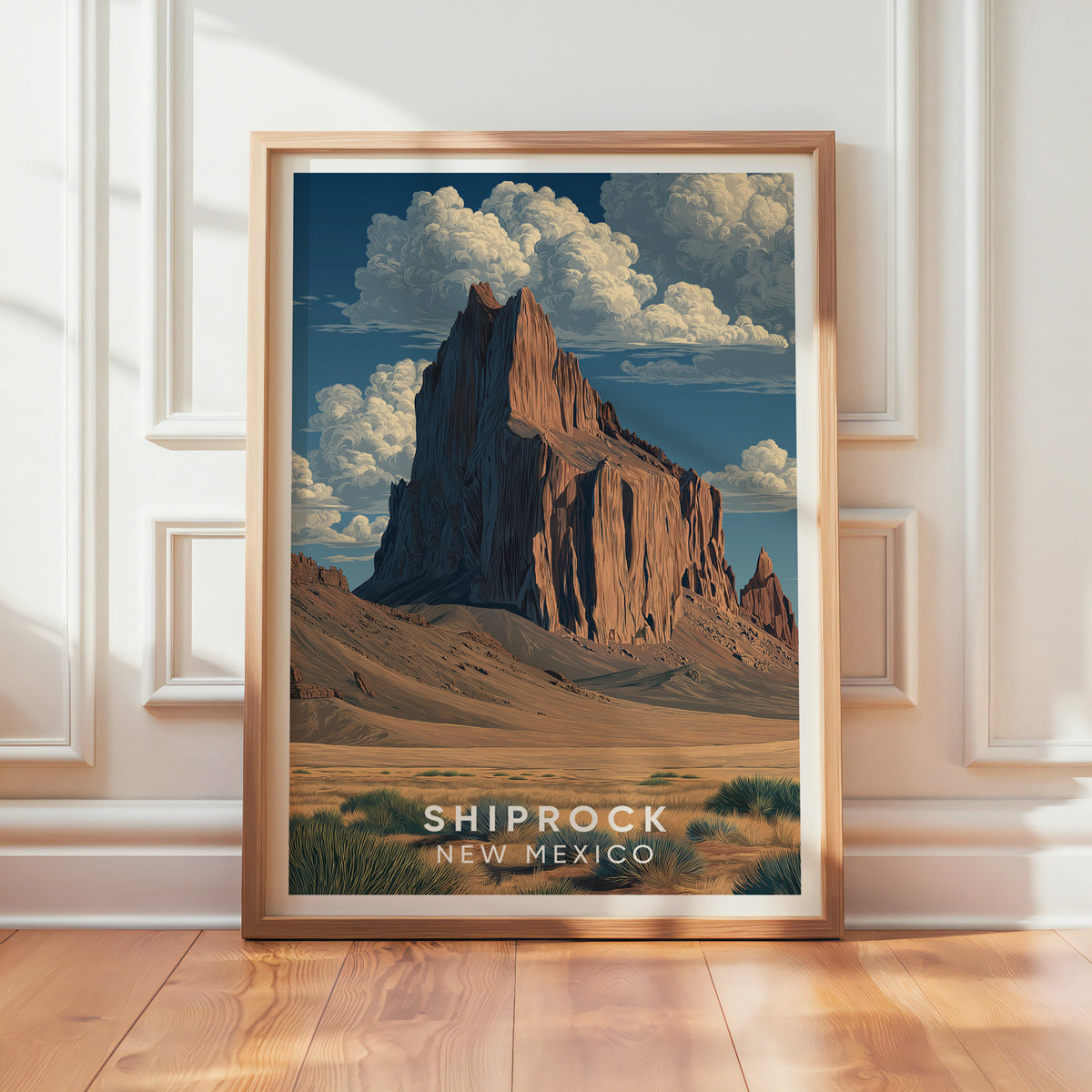 Shiprock poster in an oak frame propped against a textured white wall, sunlight falling on the floorboards
