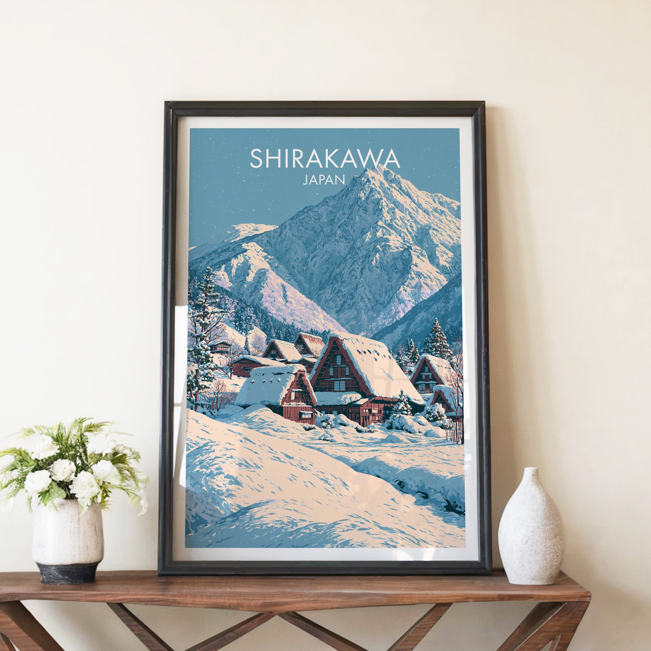 Shirakawa go Japan travel poster in a black frame on a wooden console table with white flowers