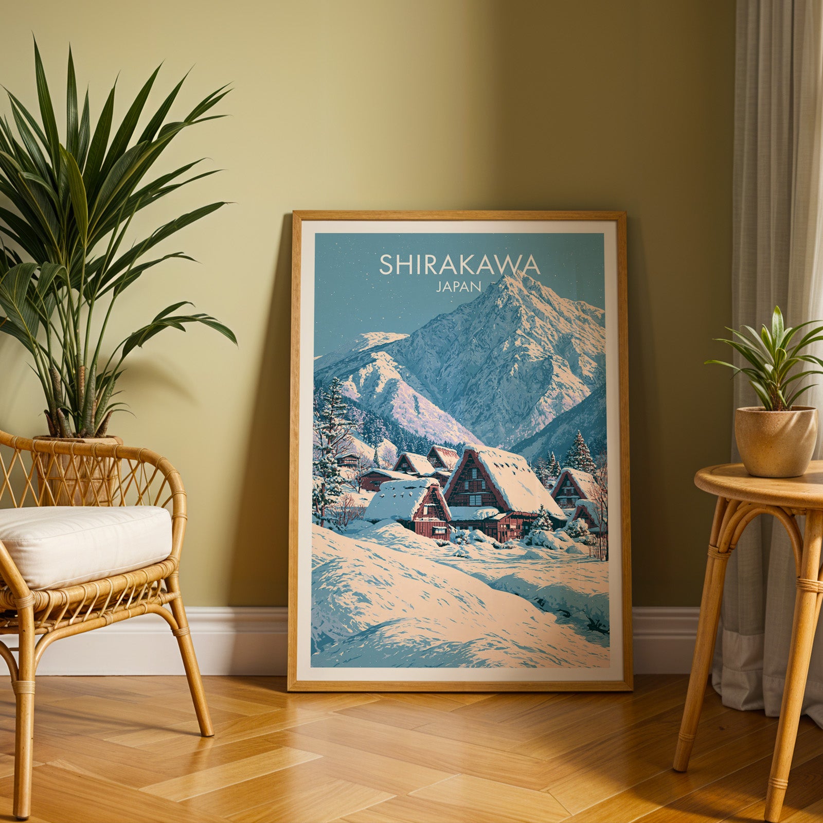 Large Shirakawa go Japan travel print in an oak frame leaning on a herringbone floor next to a rattan chair