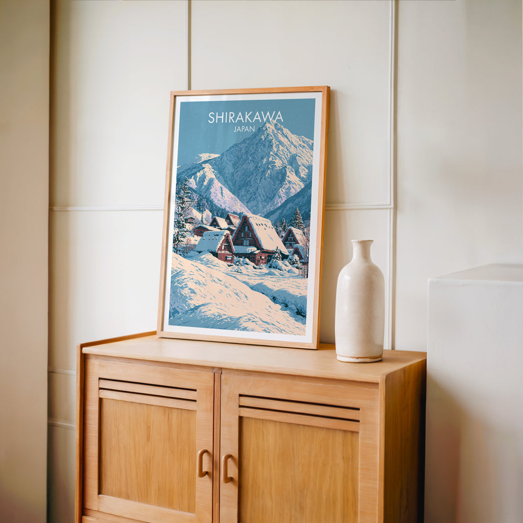 Small Shirakawa go Japan travel poster in an oak frame on a mid-century sideboard with a ceramic vase