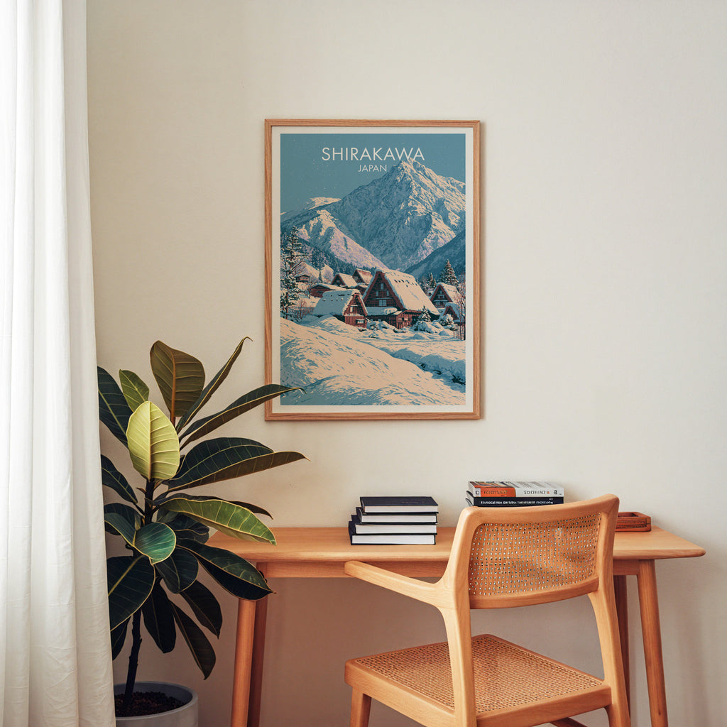 Shirakawa go Japan wall art above a wooden home office desk with a rattan chair and books