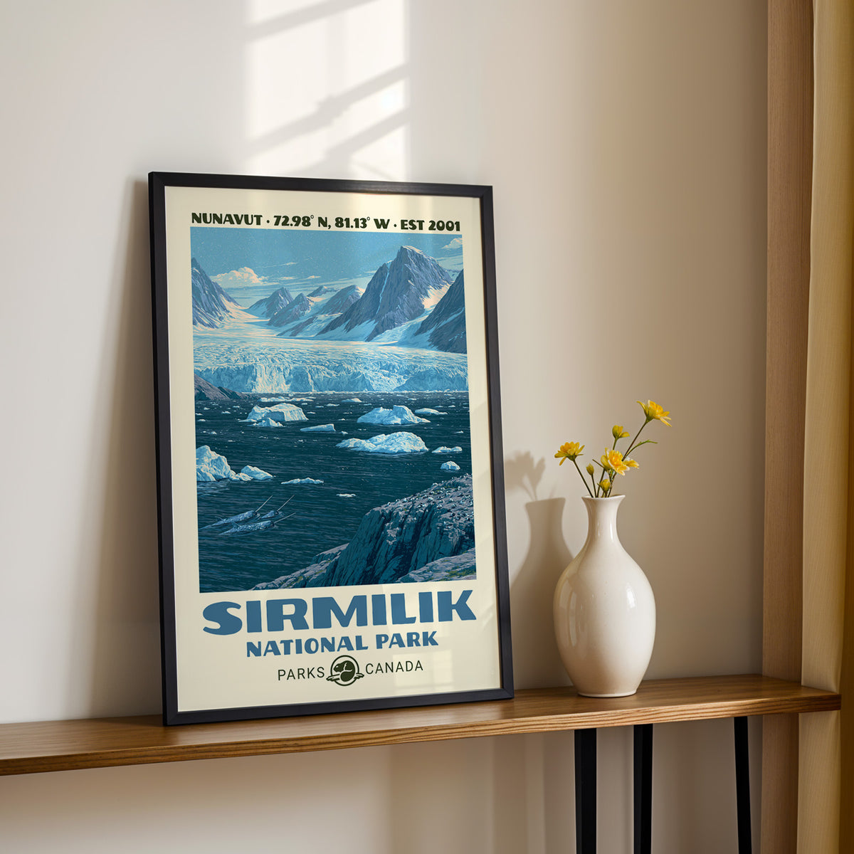 Sirmilik National Park wall art, Nunavut in a black frame on a sunlit shelf next to yellow daisies