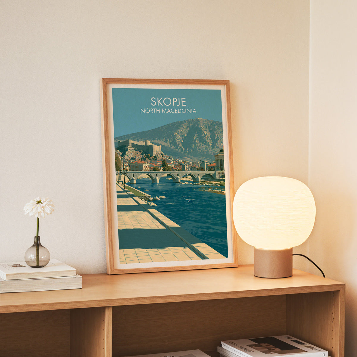 Skopje North Macedonia wall art, slim oak frame standing on an oak console beside a daisy in a glass bottle