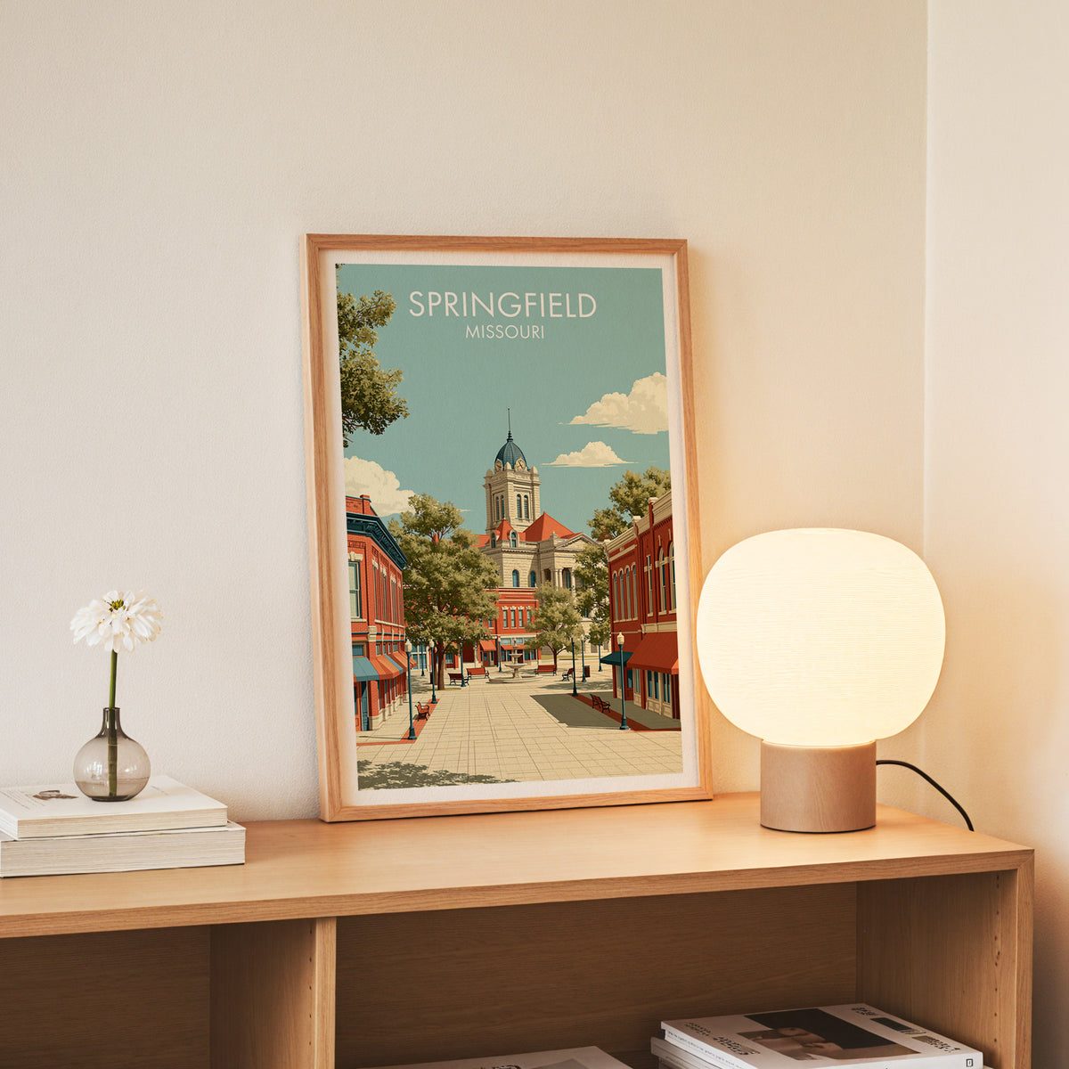 Slim oak framed Springfield print standing on a console with a globe lamp and white daisies