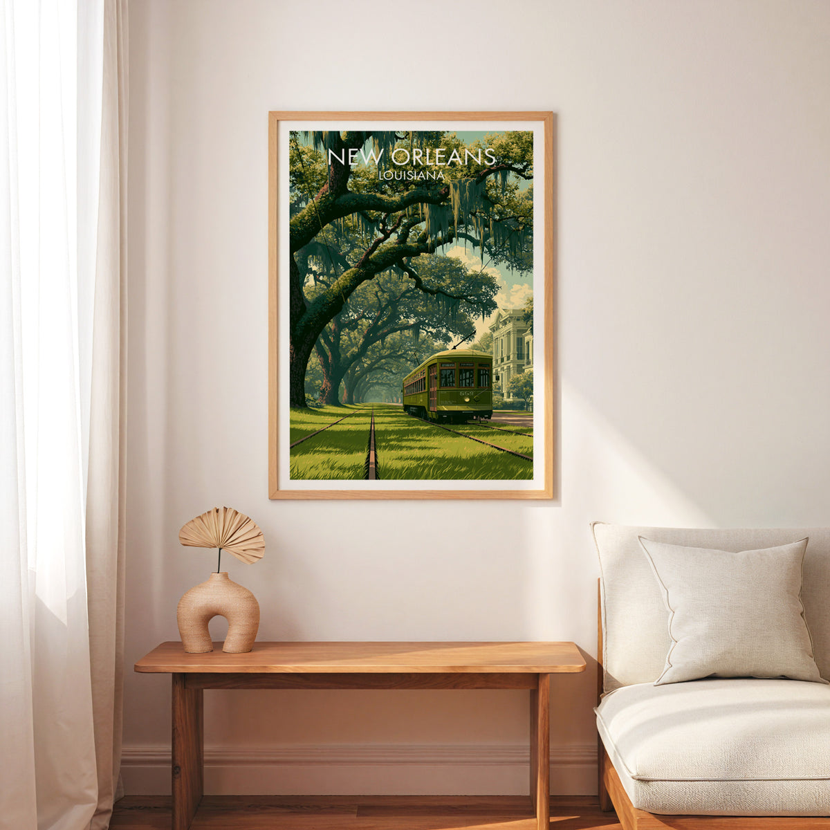 St Charles streetcar travel poster in an oak frame above a wood bench, cream armchair and a palm-leaf fan.