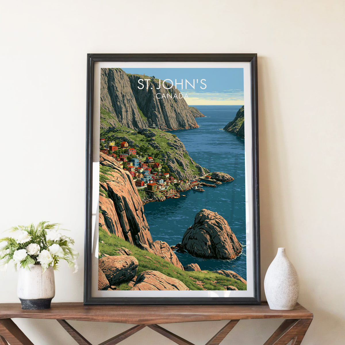 St John's Narrows cliffs print in a black frame on a walnut console beside white peonies