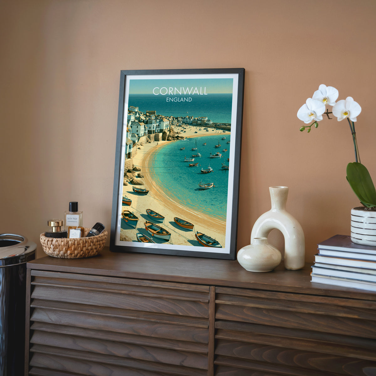 St Ives wall art, black frame on a walnut sideboard against a terracotta wall with a white orchid