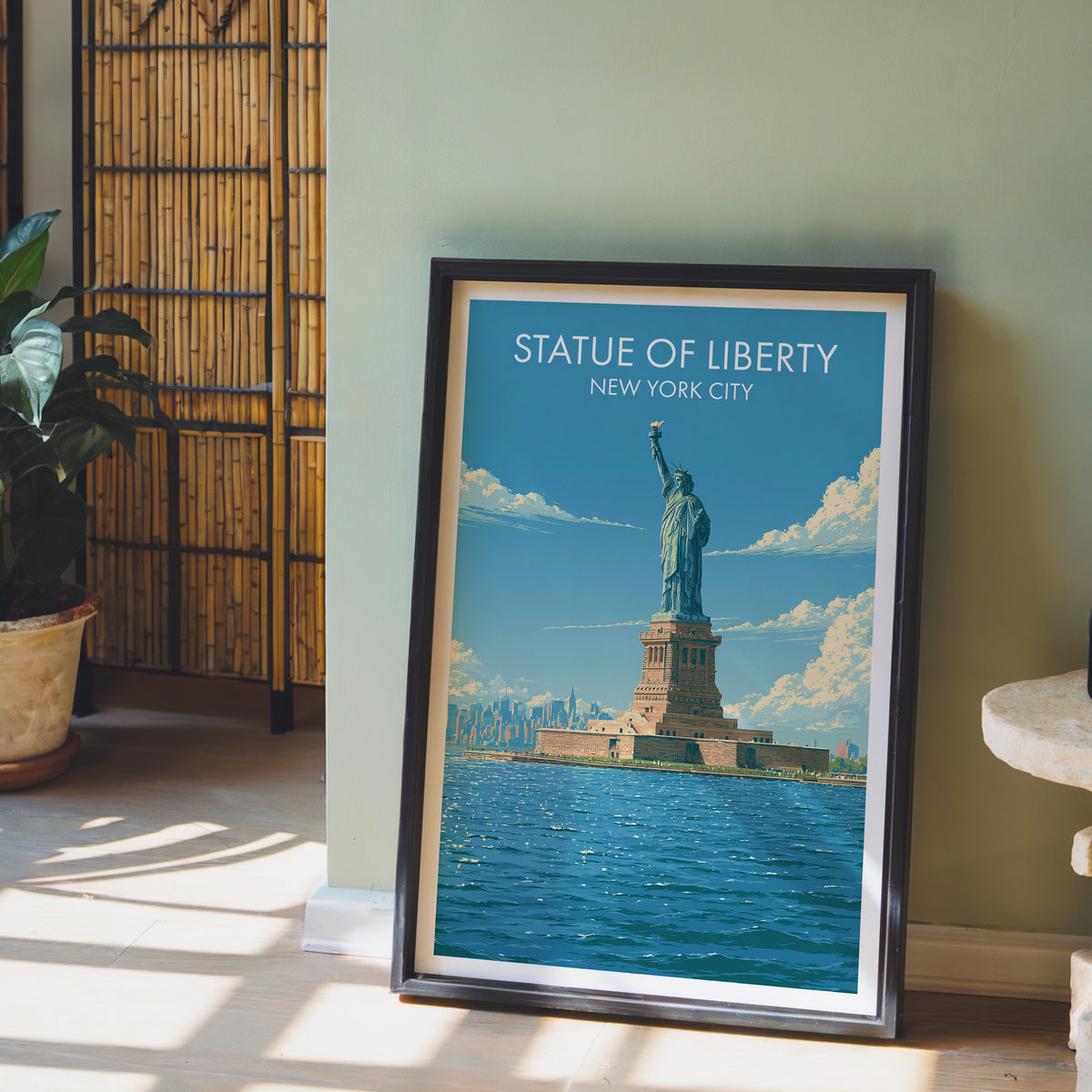 Statue of Liberty print in a black frame on a sage green wall with a bamboo screen and a potted orchid.
