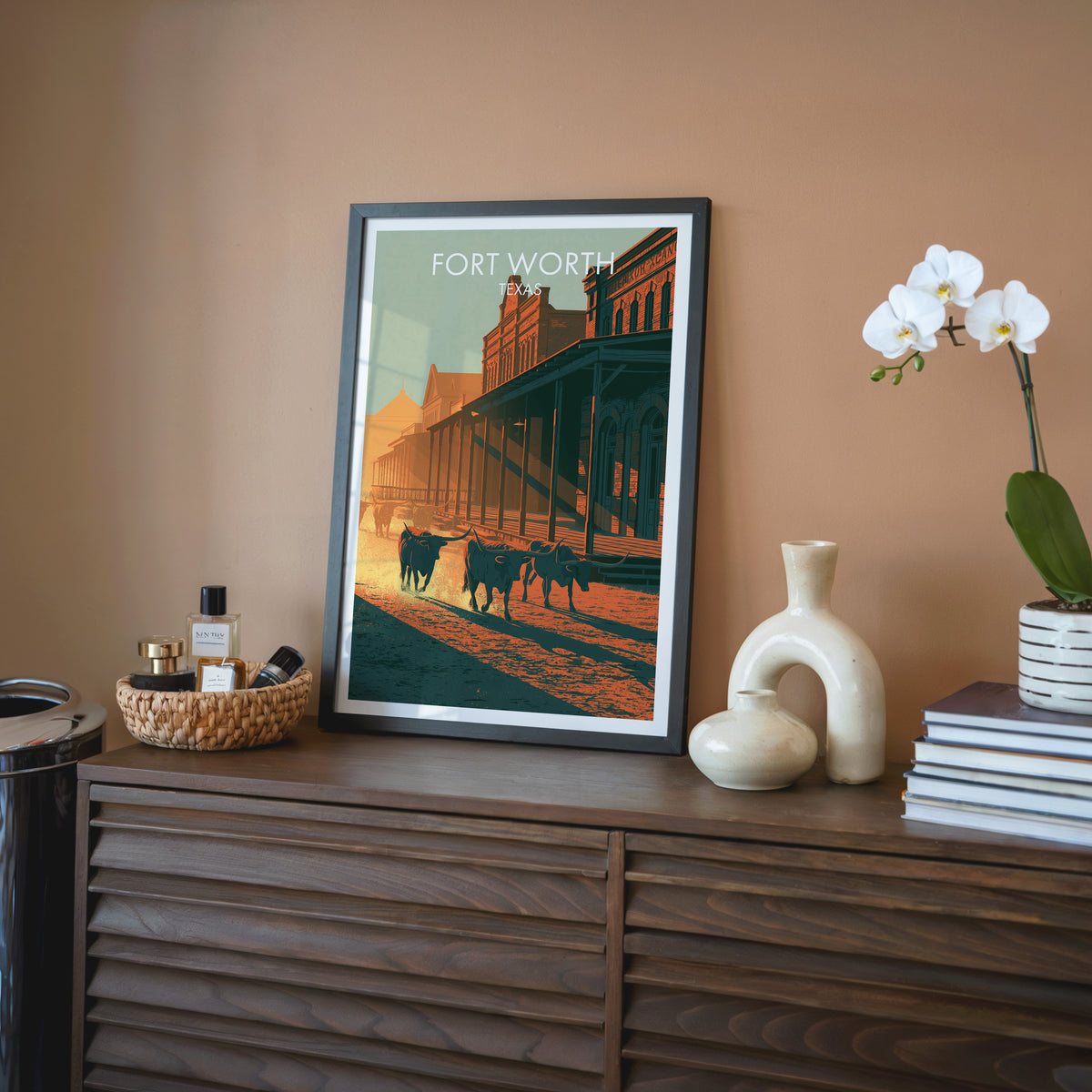 Fort Worth Stockyards wall art in a black frame on a walnut sideboard against a terracotta wall.