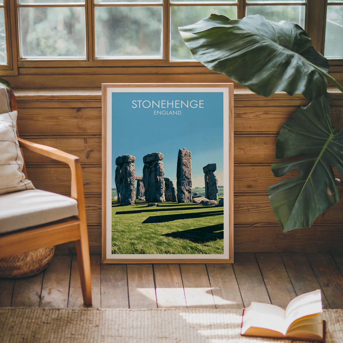 Stonehenge travel poster, oak frame leaning on a wood-panelled sunroom wall by a mid-century armchair