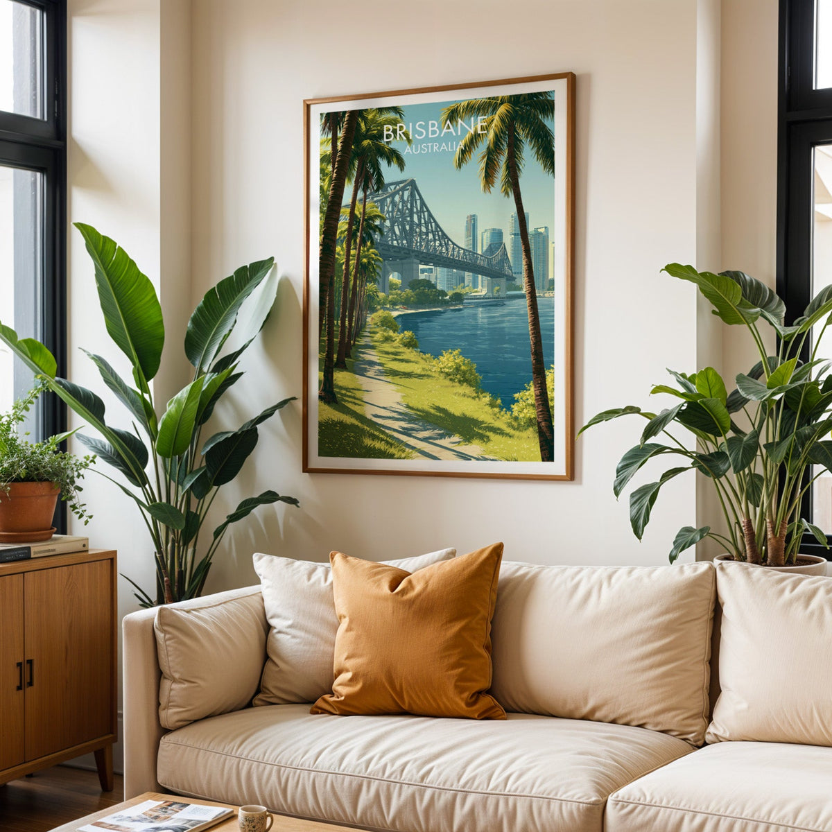 Brisbane travel poster in an oak frame above a cream sofa with a burnt-orange cushion and tall tropical plants
