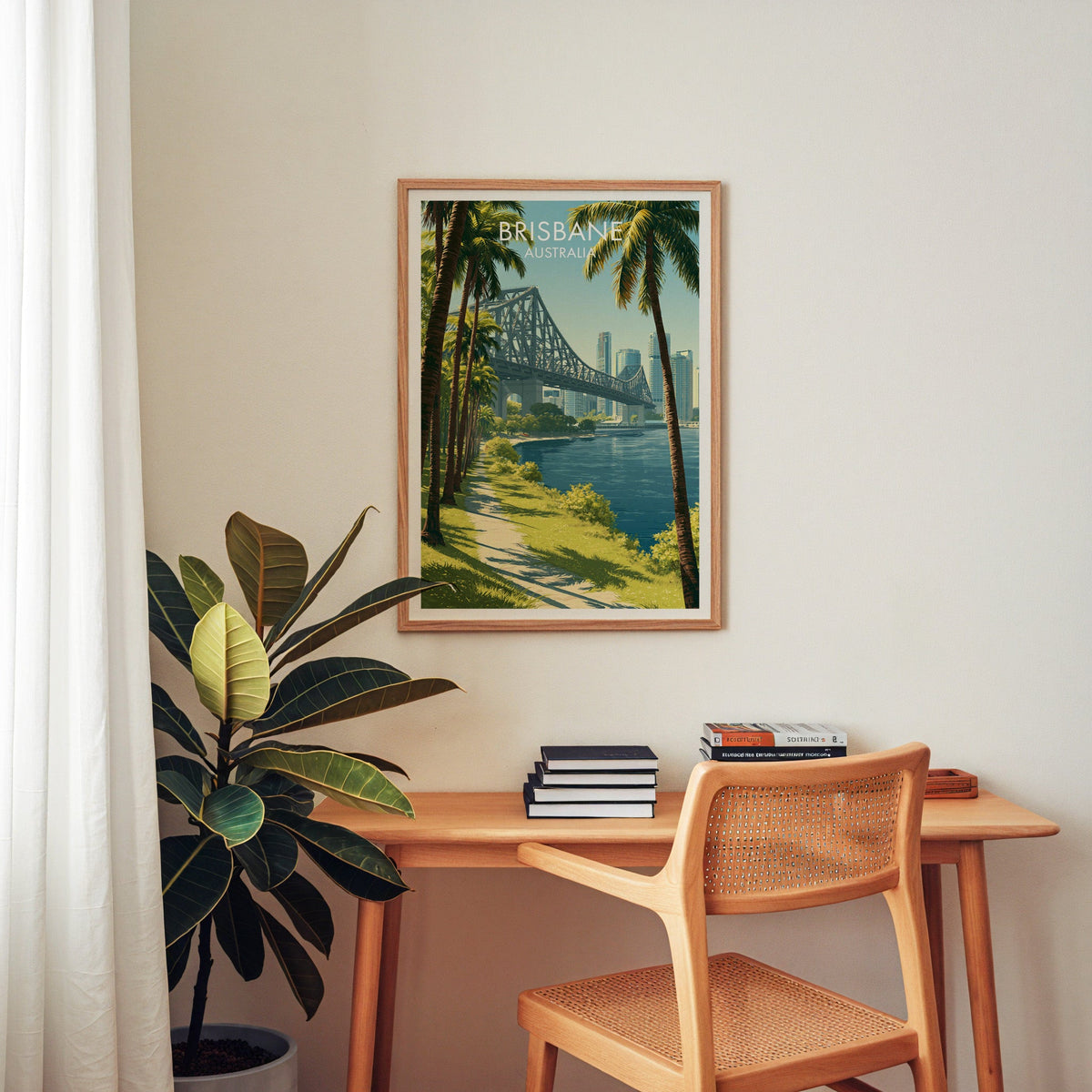 Brisbane city and bridge art in an oak frame above a wooden desk with a cane chair and rubber plant