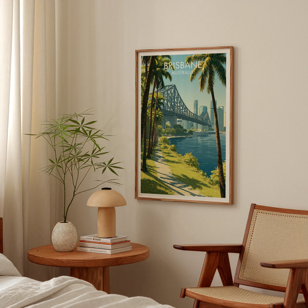 Story Bridge river print in an oak frame in a bedroom above a round table with a mushroom lamp and cane chair