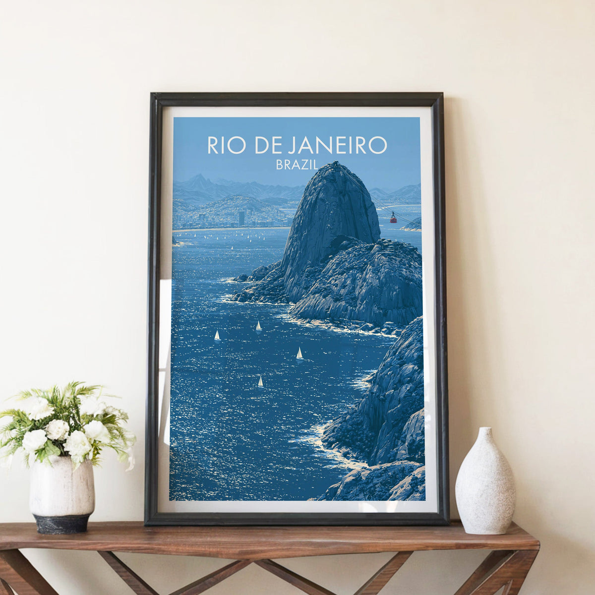 Rio granite dome print in a black frame on an X-leg wood console with white blooms in a ceramic vase