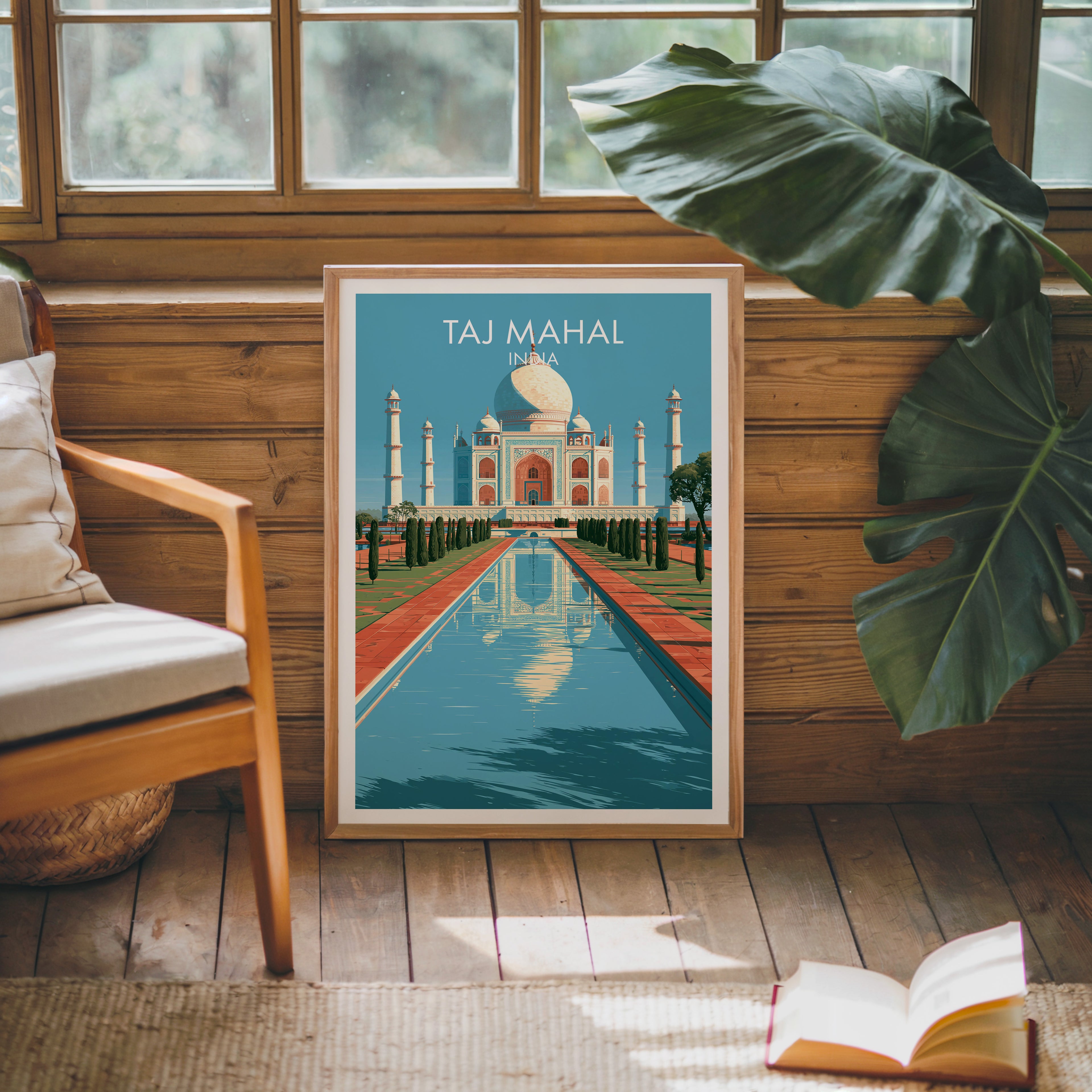 Framed Taj Mahal Agra India poster leaning against a timber cabin wall with monstera leaves and an open book