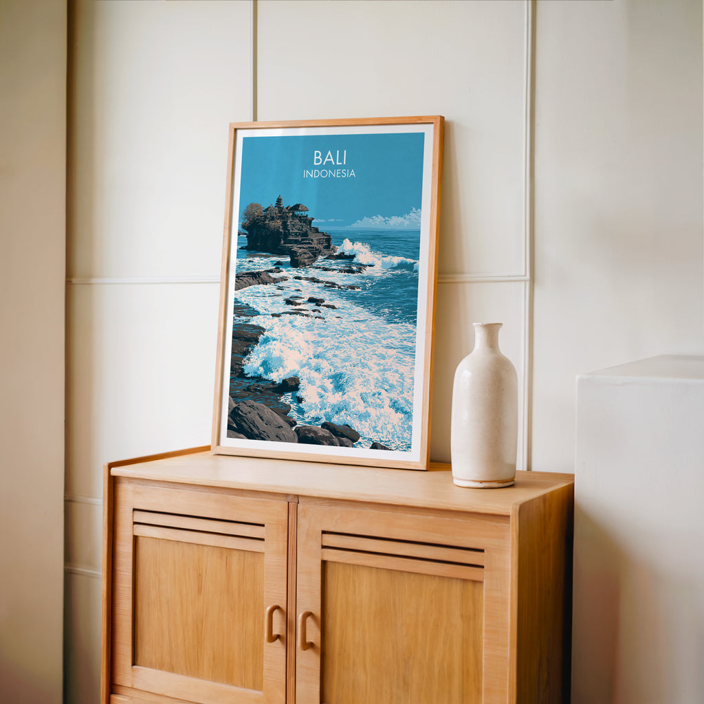 Small Tanah Lot Bali Indonesia travel poster in an oak frame on a mid-century sideboard with a ceramic vase
