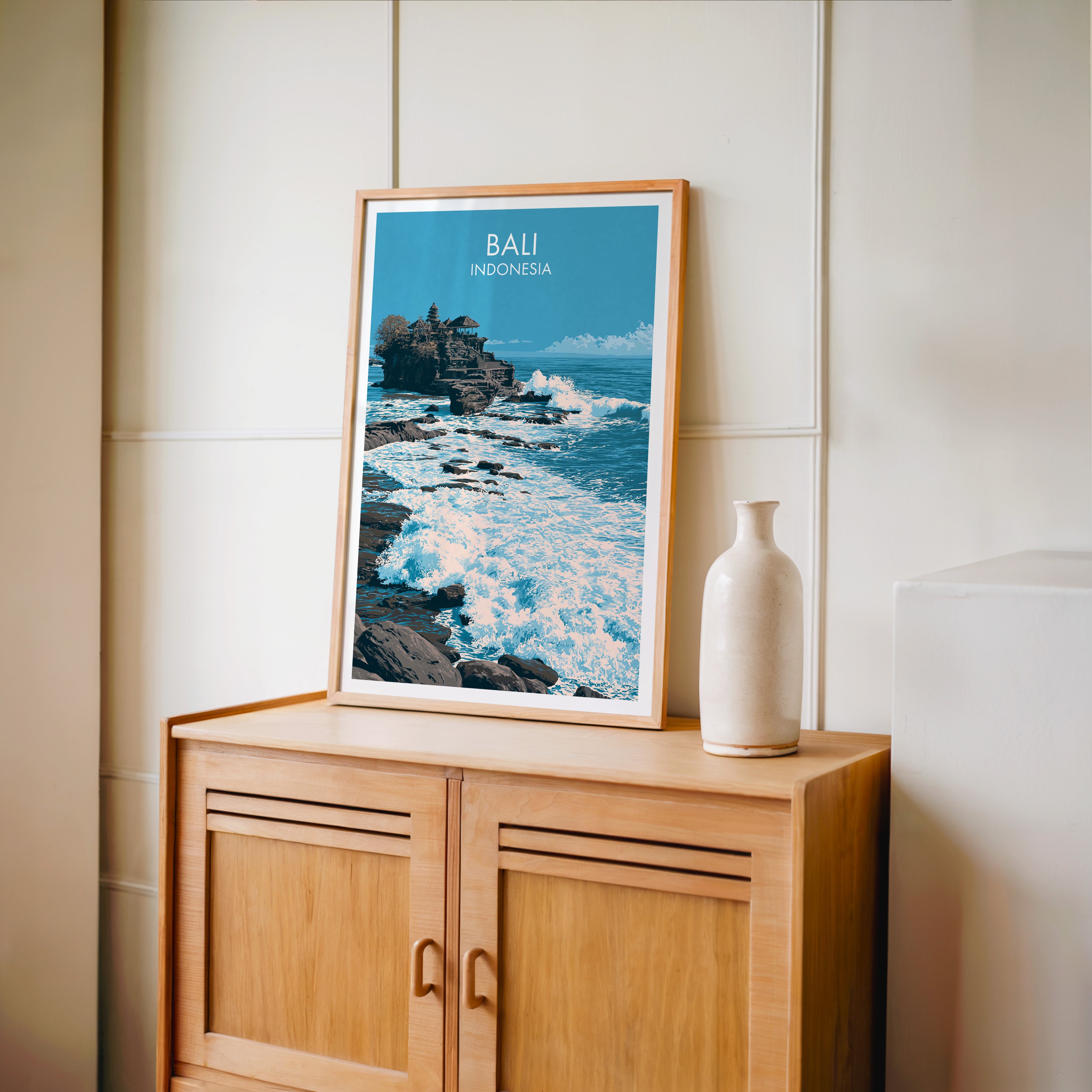 Small Tanah Lot Bali Indonesia travel poster in an oak frame on a mid-century sideboard with a ceramic vase