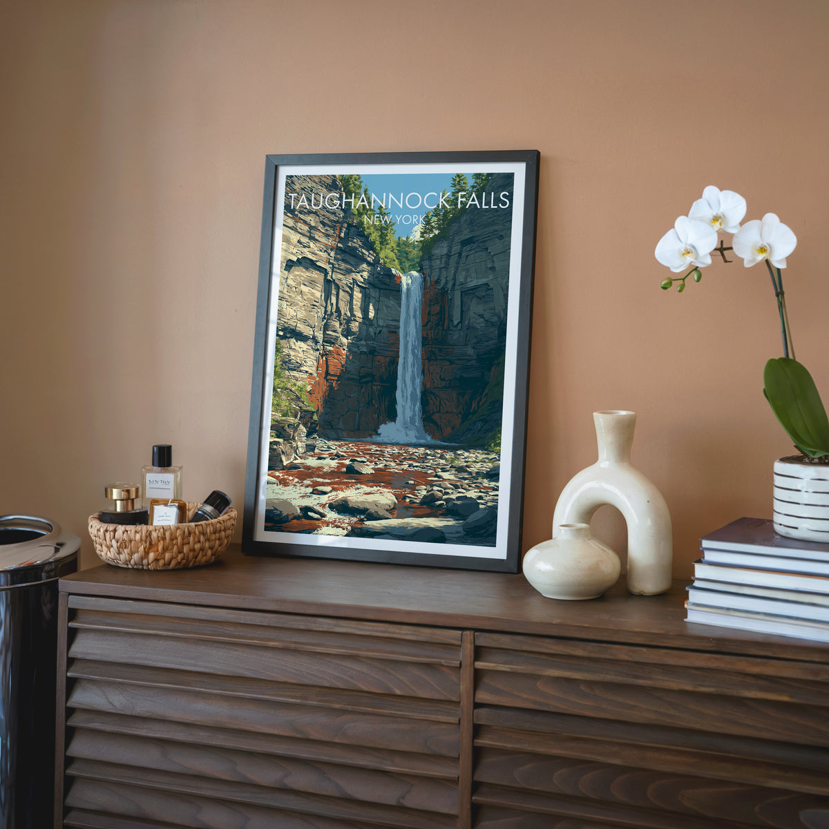 Finger Lakes gorge print in a black frame on a walnut sideboard, terracotta wall, orchid and ceramic jar