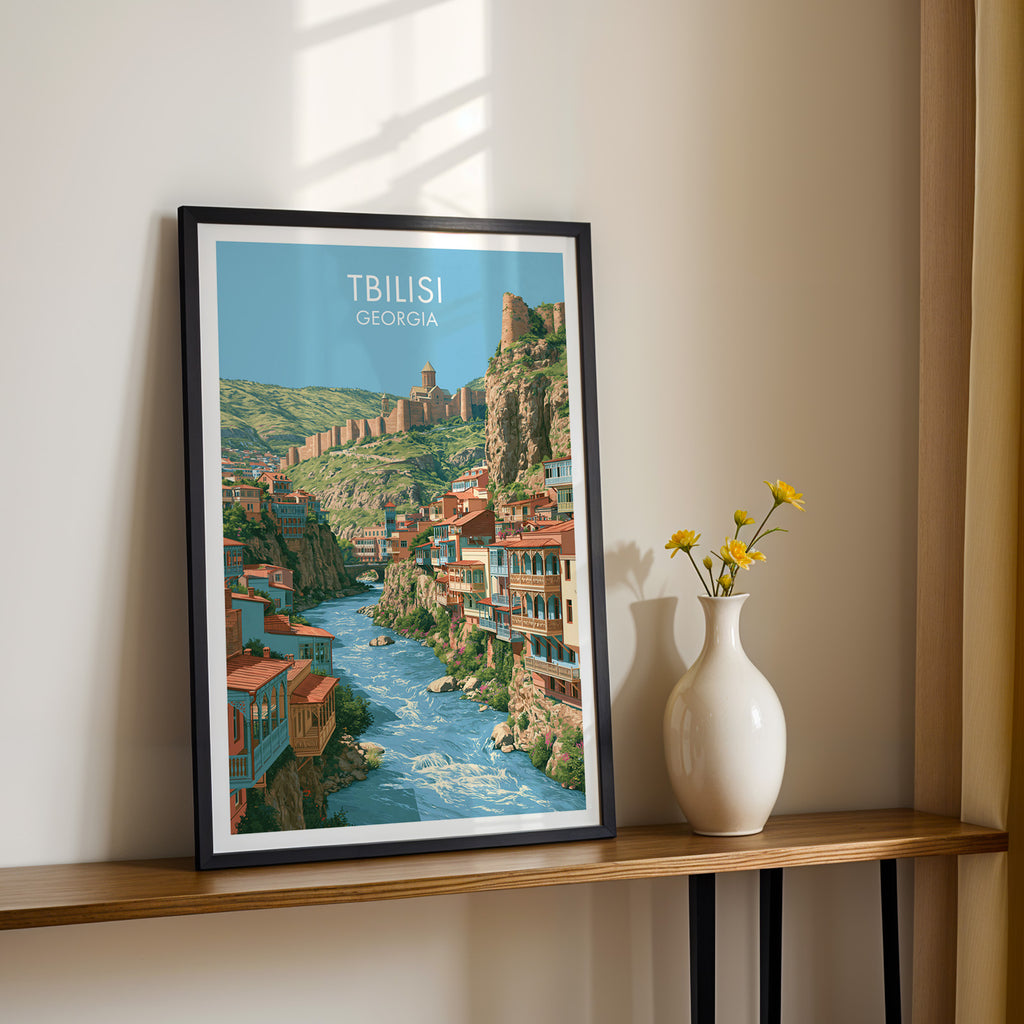 Black framed Tbilisi Georgia print on a narrow hallway console in sunlight, styled with yellow flowers
