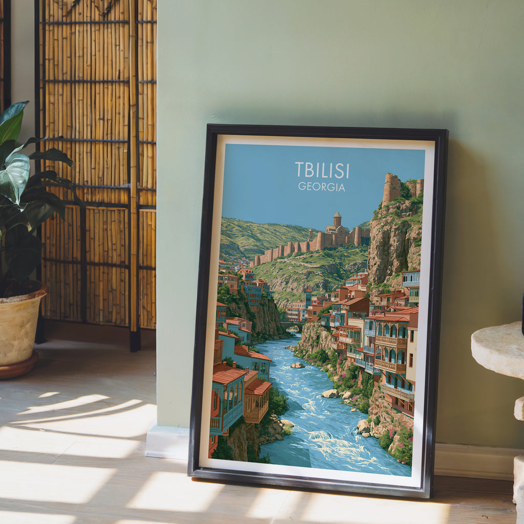 Tbilisi Georgia wall art in a black frame leaning against a sage green wall beside a bamboo screen