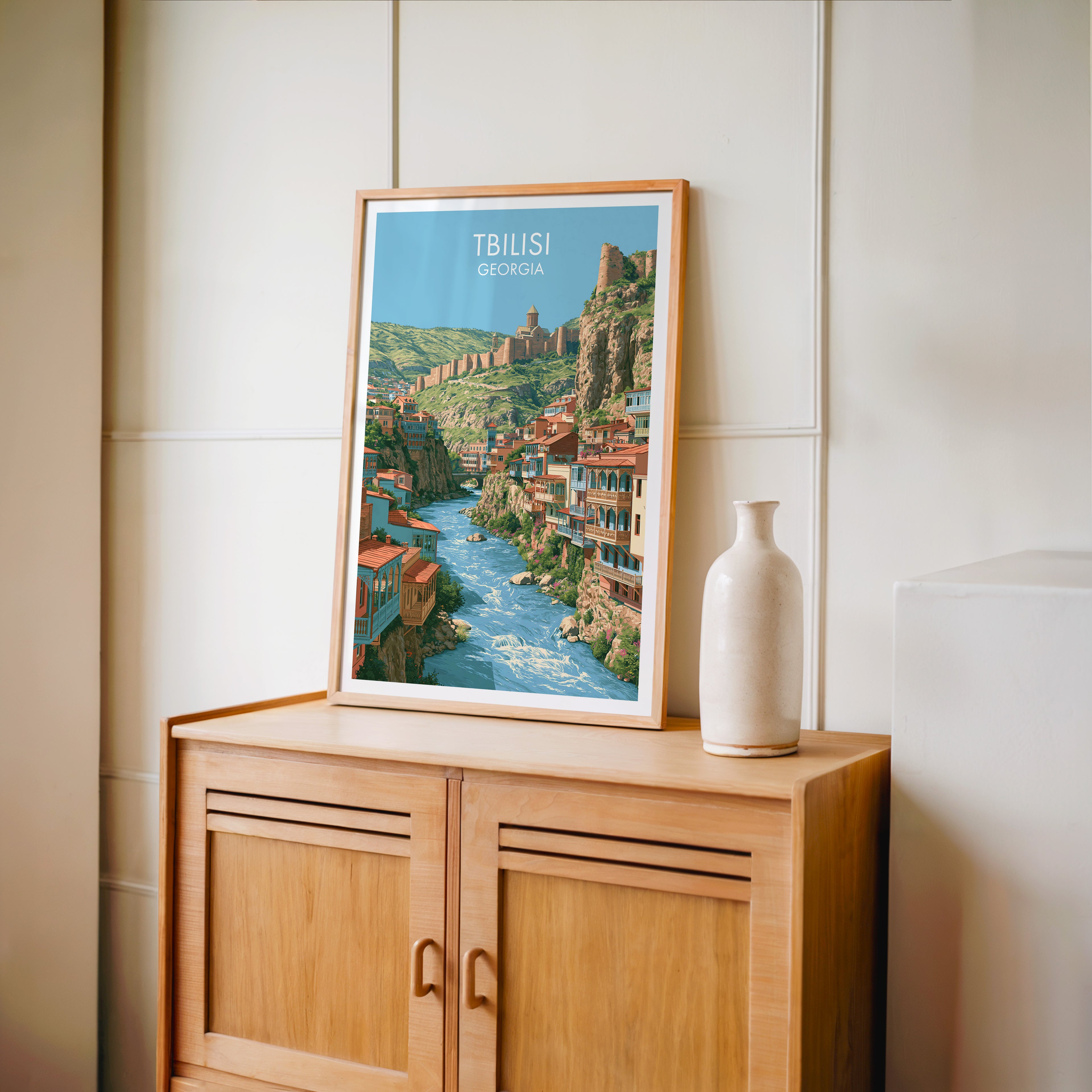 Small Tbilisi Georgia travel poster in an oak frame on a mid-century sideboard with a ceramic vase
