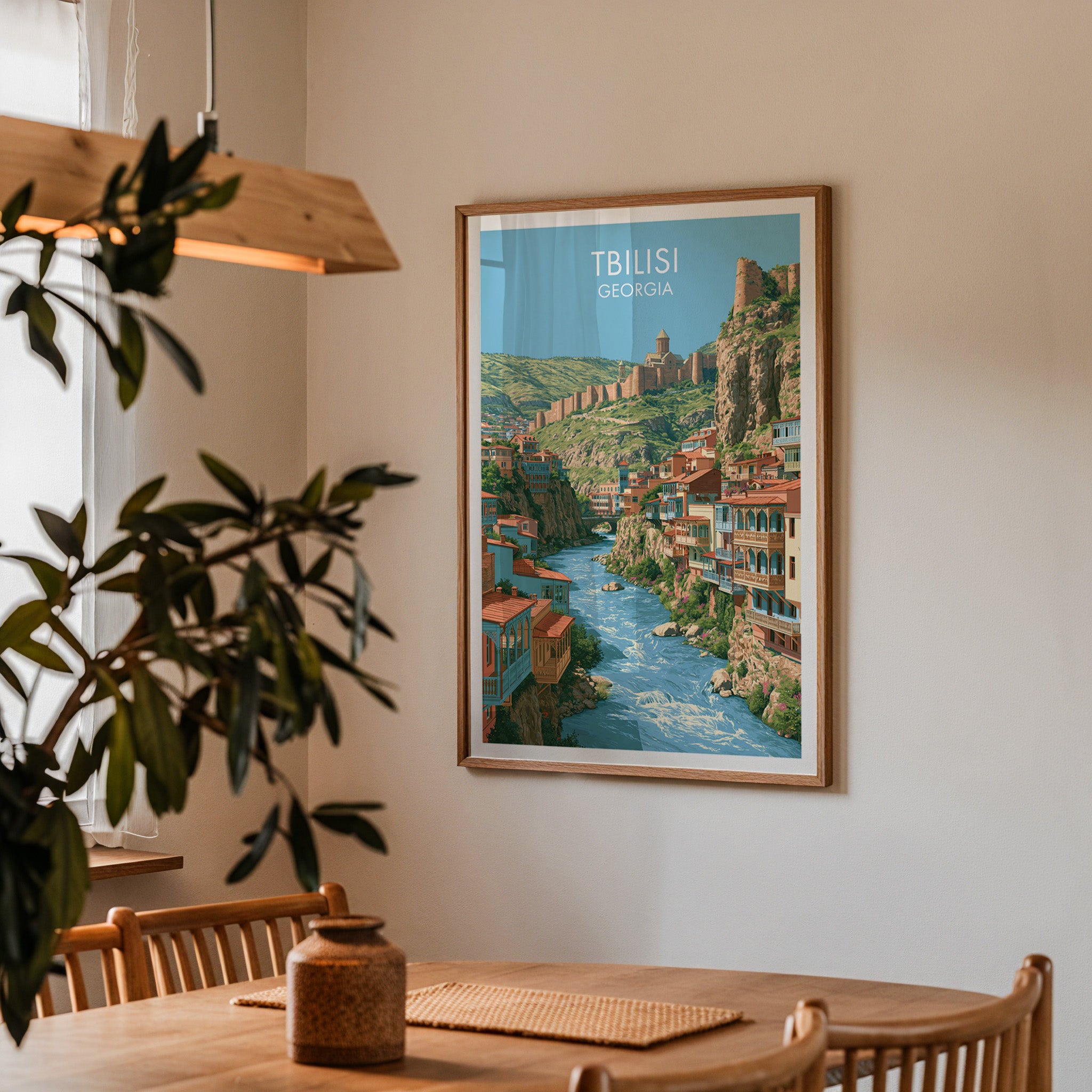 Framed Tbilisi Georgia print on a dining room wall above an oak table in warm afternoon light