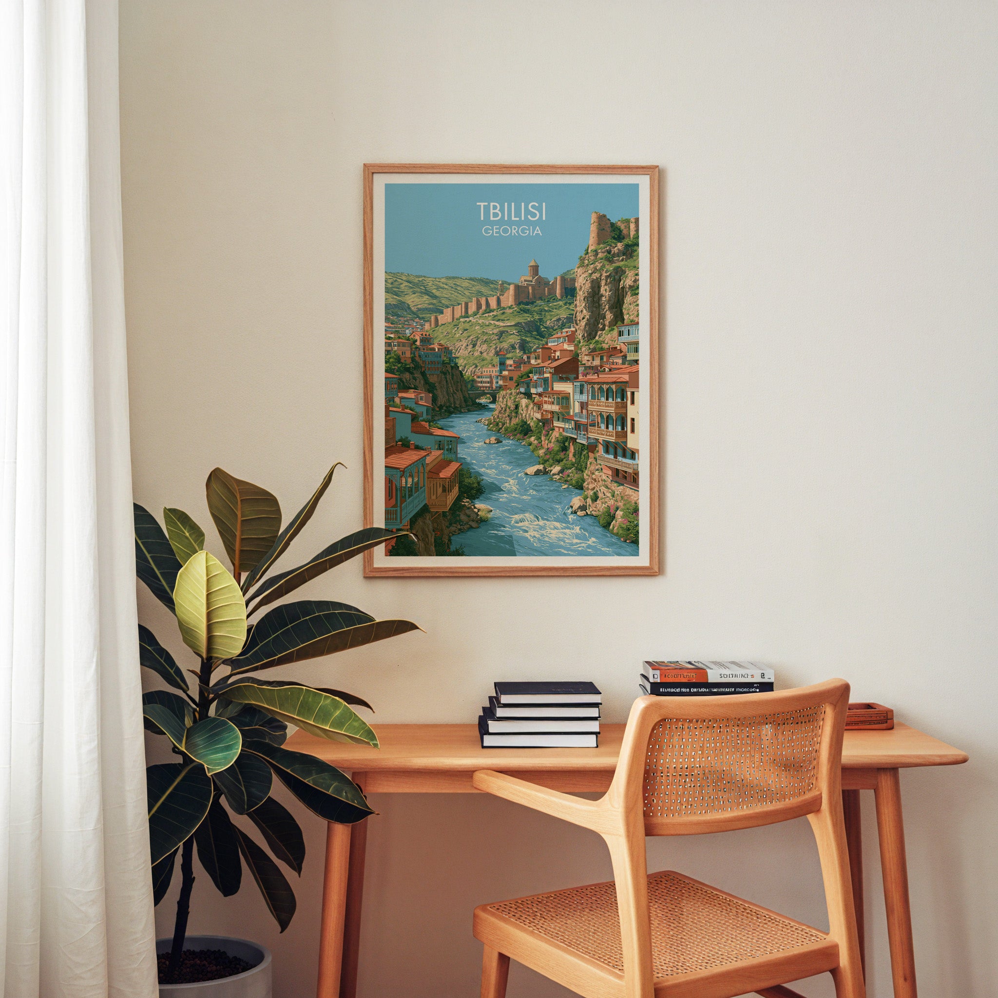 Tbilisi Georgia wall art above a wooden home office desk with a rattan chair and books