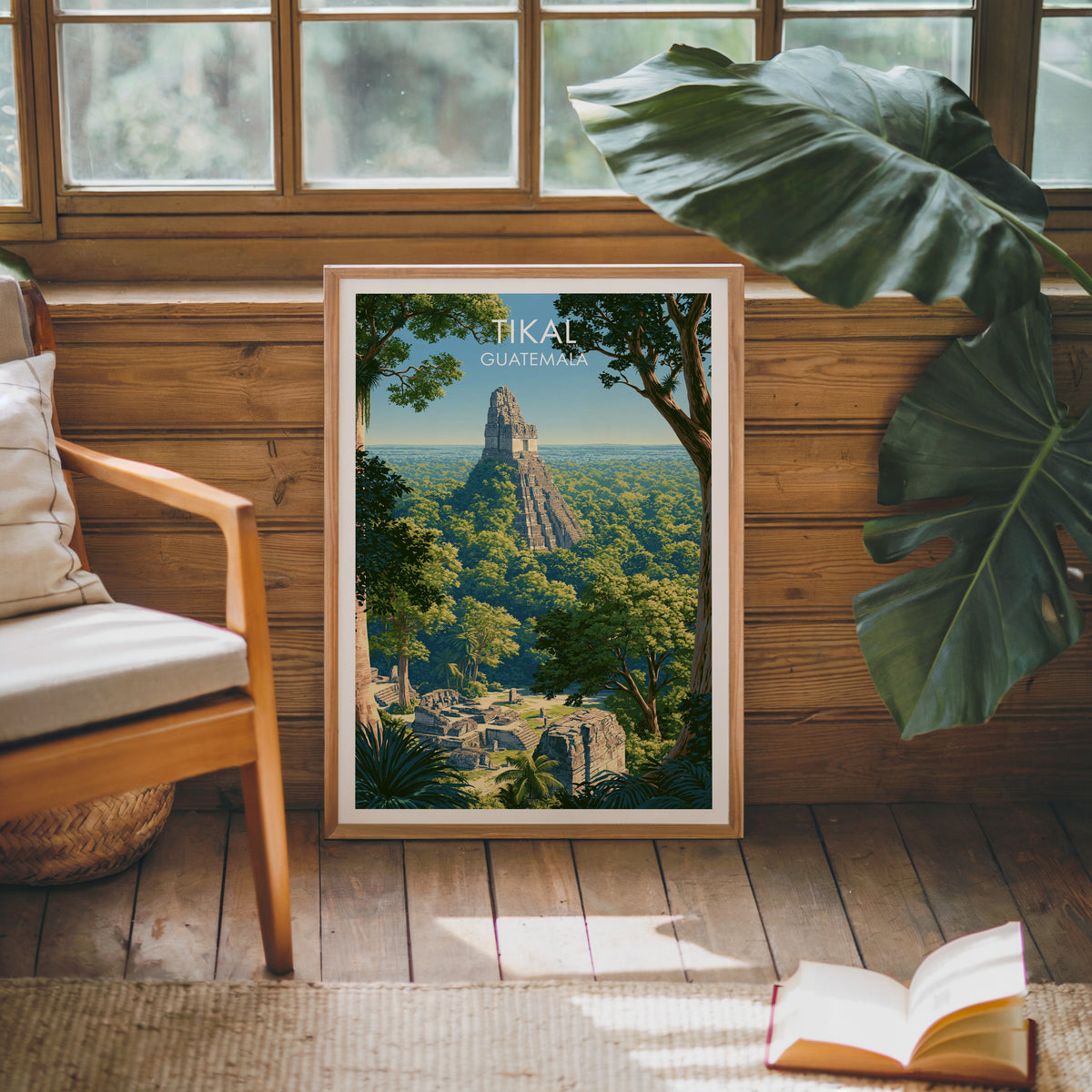 Tikal poster in an oak frame leaning on a pine cabin wall with a wooden armchair, monstera leaf and jute rug
