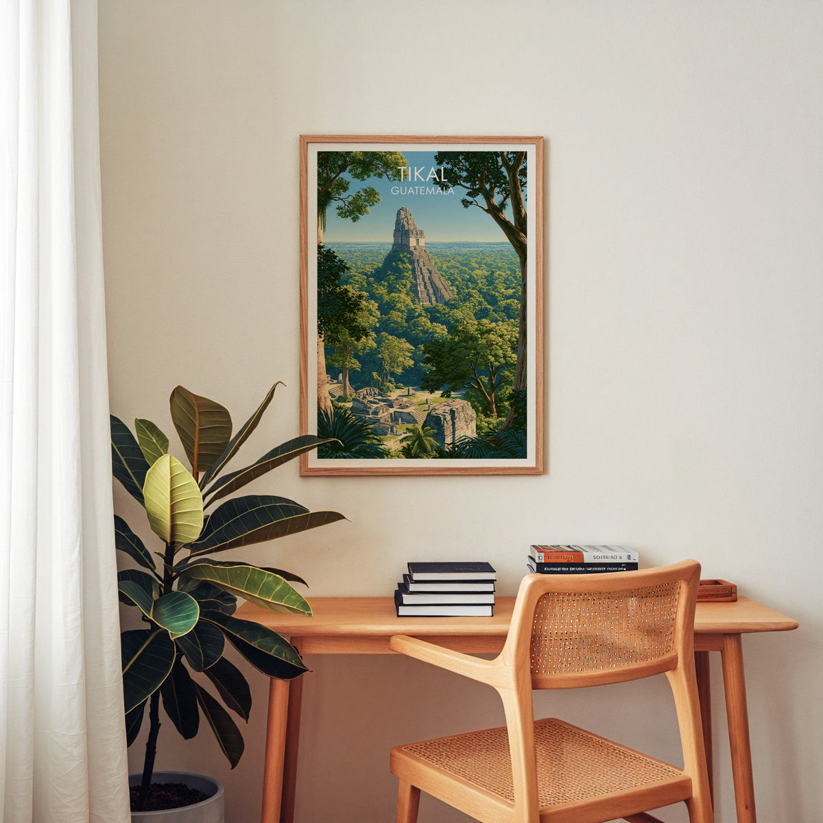 Central America travel print in an oak frame above a home-office desk with a cane chair and rubber plant
