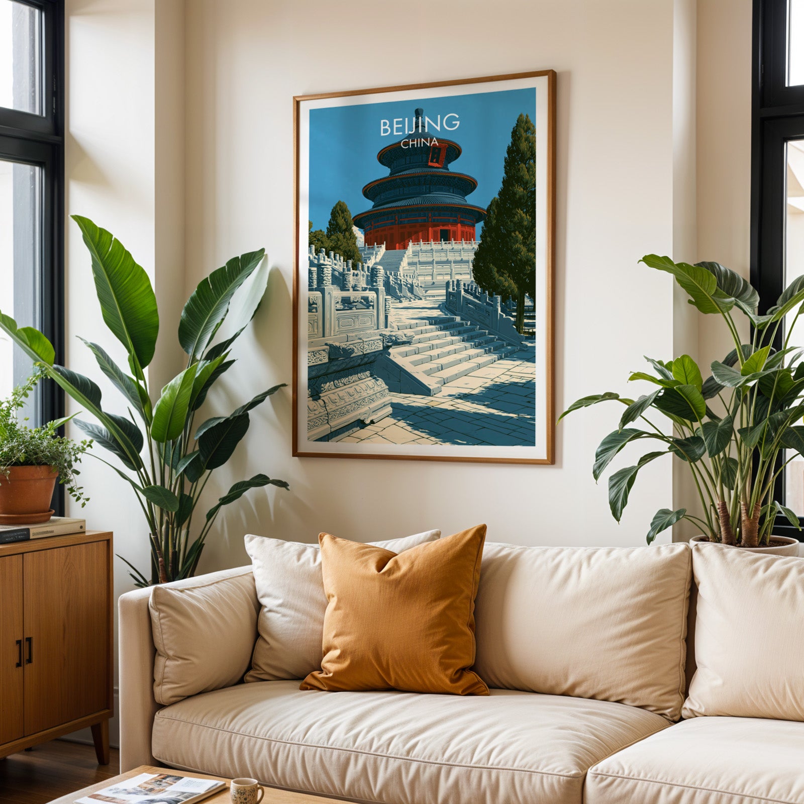 Framed Temple of Heaven Beijing wall art hanging above a cream sofa in a bright living room with tropical plants