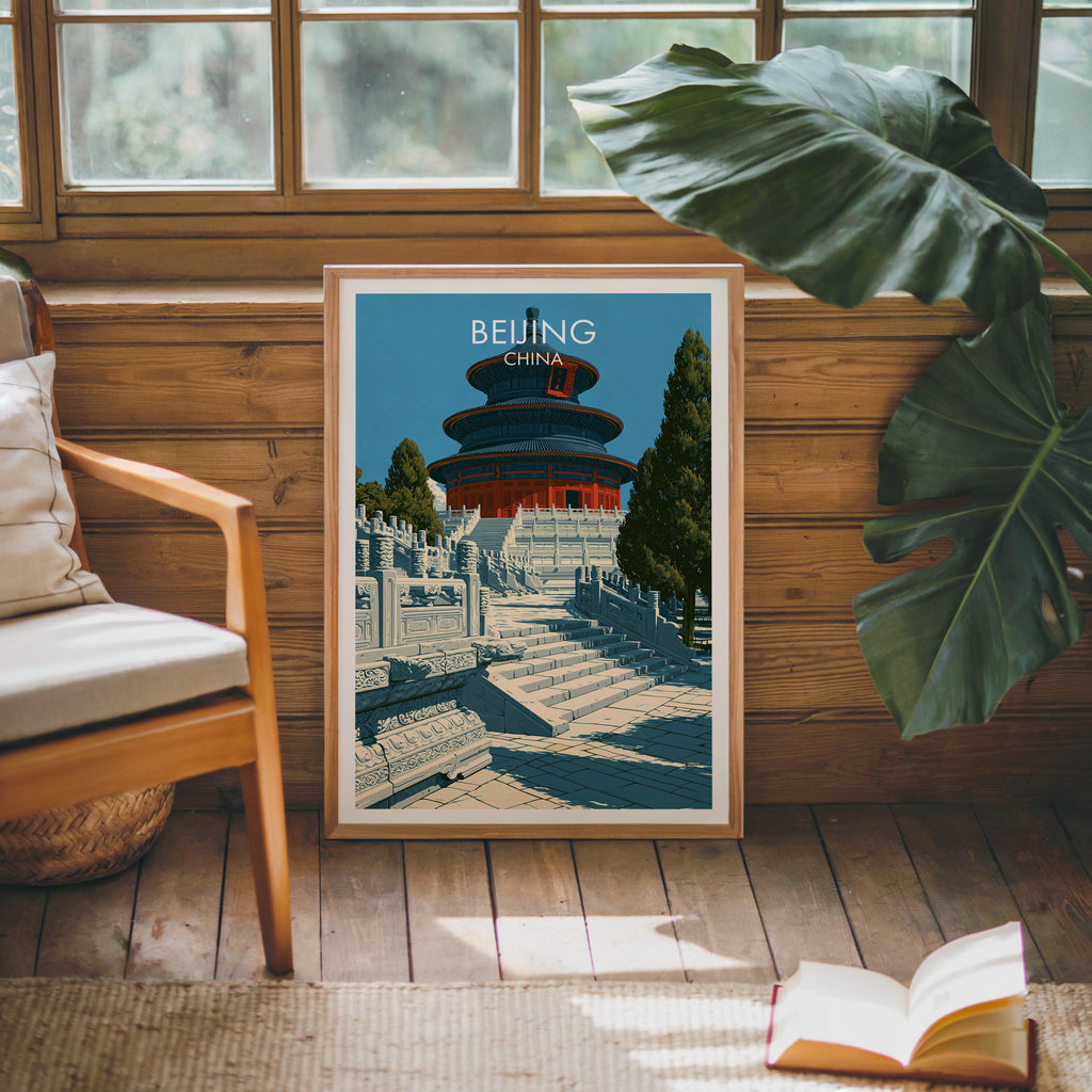 Framed Temple of Heaven Beijing poster leaning against a timber cabin wall with monstera leaves and an open book