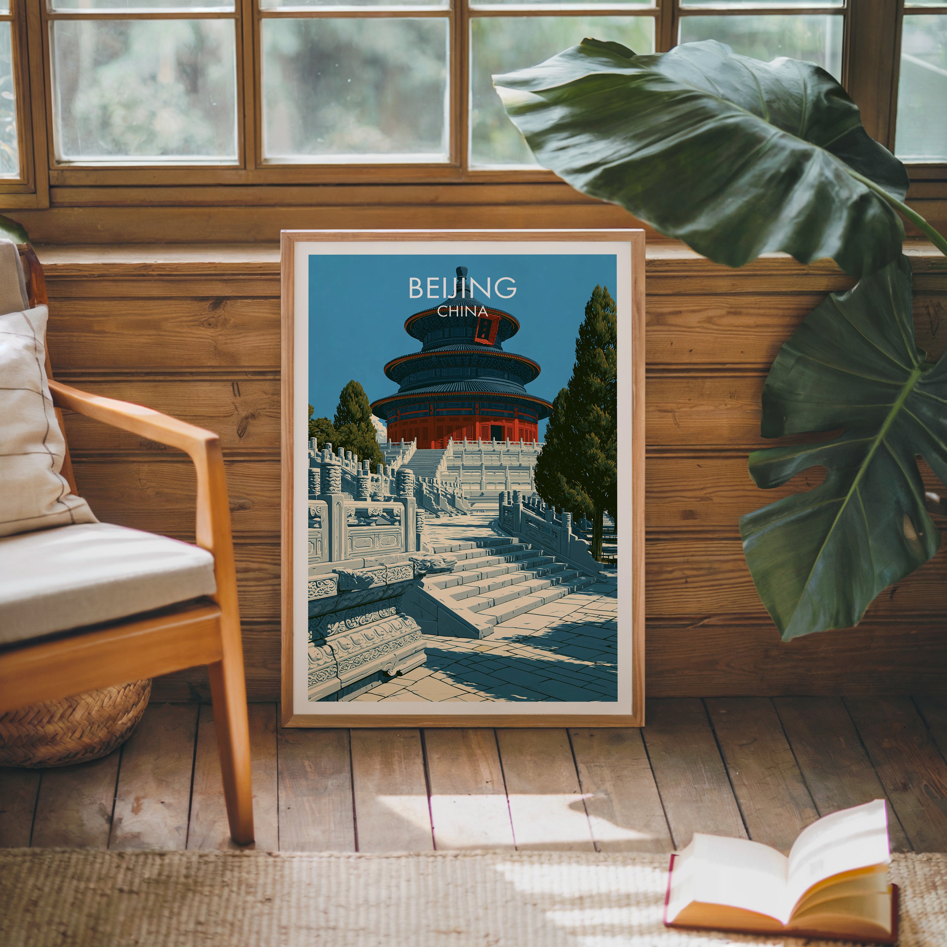 Framed Temple of Heaven Beijing poster leaning against a timber cabin wall with monstera leaves and an open book