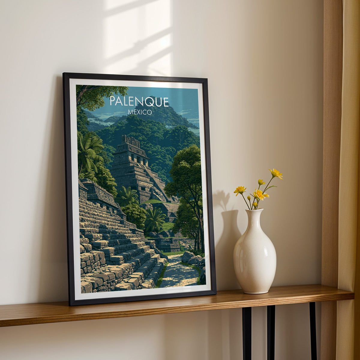 Grey stone temple and jungle hills, black frame on a wood shelf with yellow daisies on a cream wall