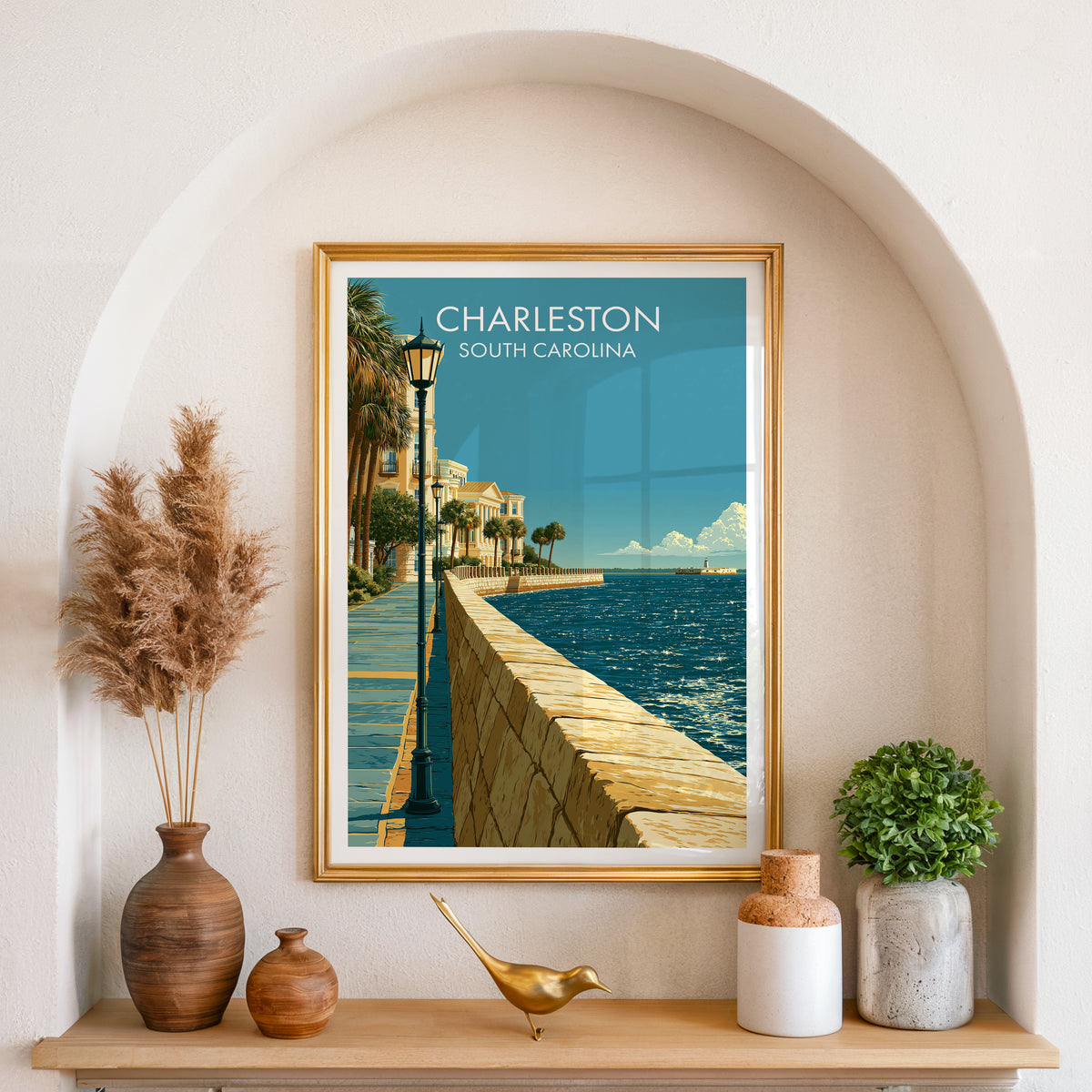 Palmetto seawall print in a gold frame set in an arched wall niche with pampas grass and a brass bird.