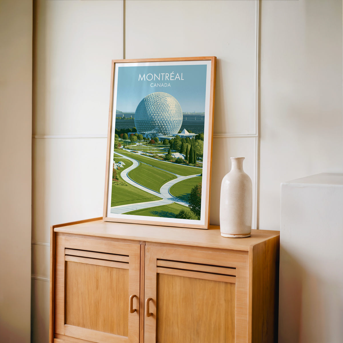 Ile Sainte-Helene park wall art in an oak frame on a light wood cabinet beside a stoneware vase