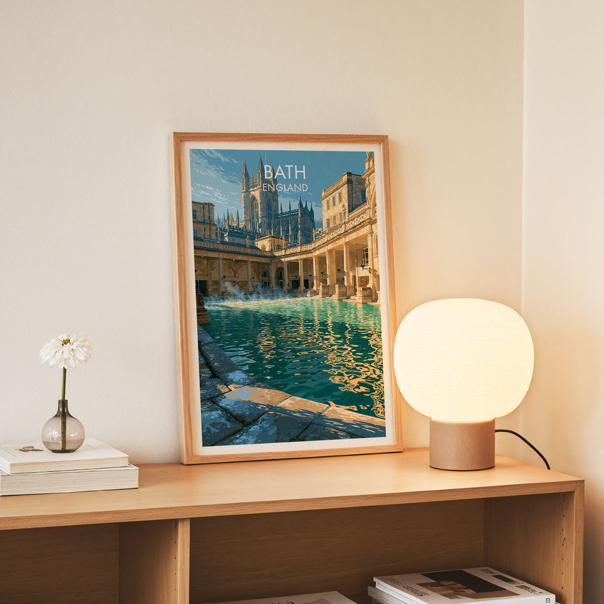 Roman Baths wall art, slim oak frame standing on an oak console beside a daisy in a glass bottle