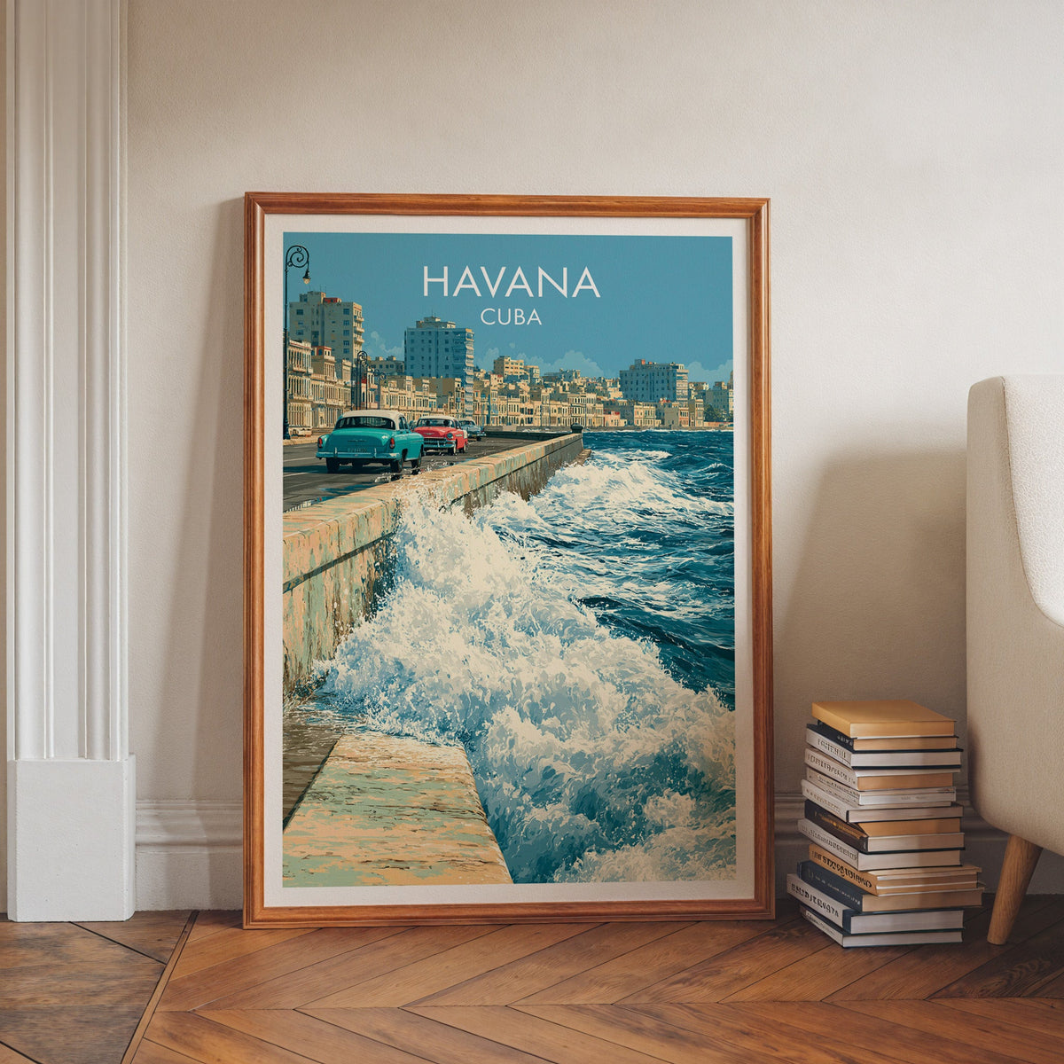 Crashing waves on the Malecon in a walnut frame on herringbone floor with stacked books and a pale armchair