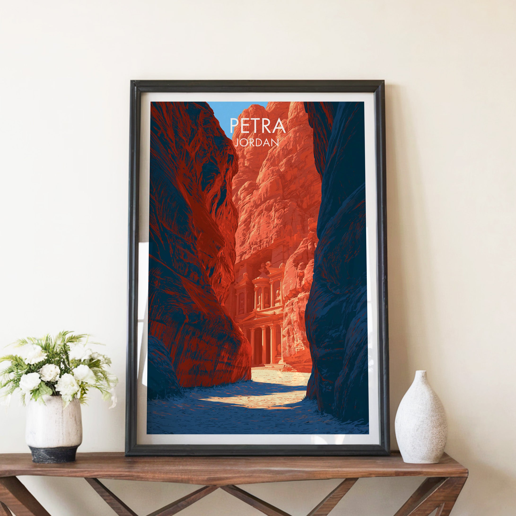 Petra Jordan Treasury travel poster in a black frame on a wooden console table with white flowers