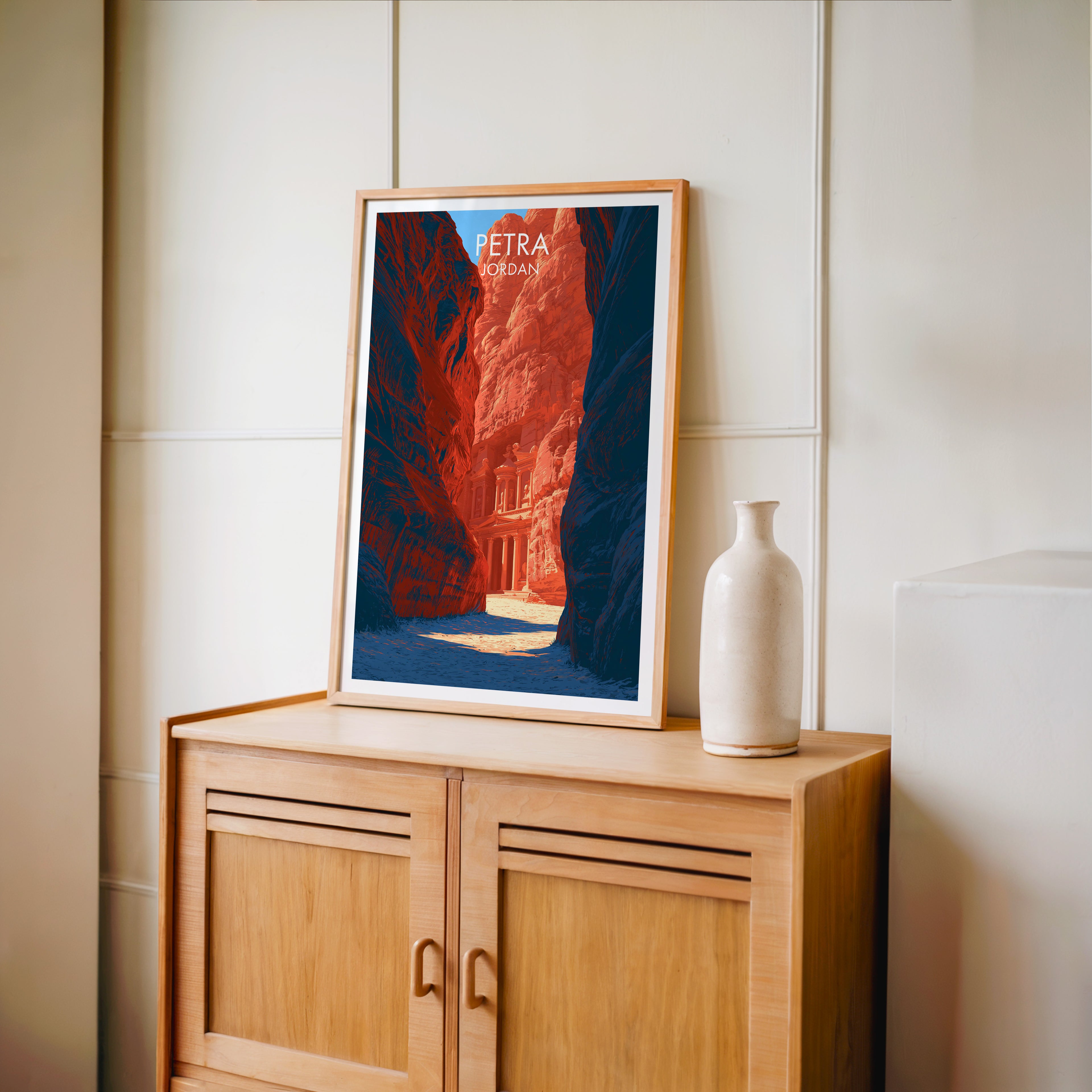 Small Petra Jordan Treasury travel poster in an oak frame on a mid-century sideboard with a ceramic vase