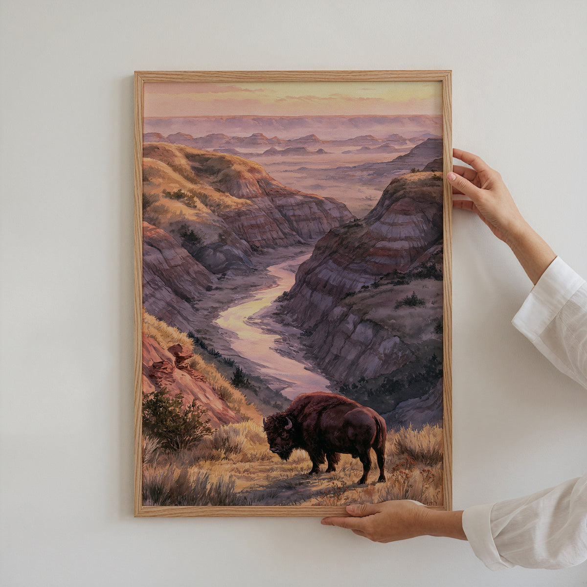 Hands holding an oak-framed Theodore Roosevelt watercolor art print against a plain white wall