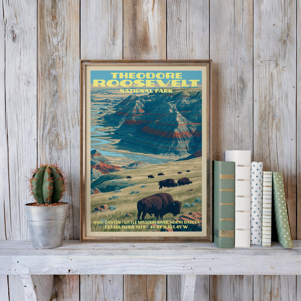 Wind Canyon badlands print in a slim gold frame on a whitewashed plank wall beside a cactus and books