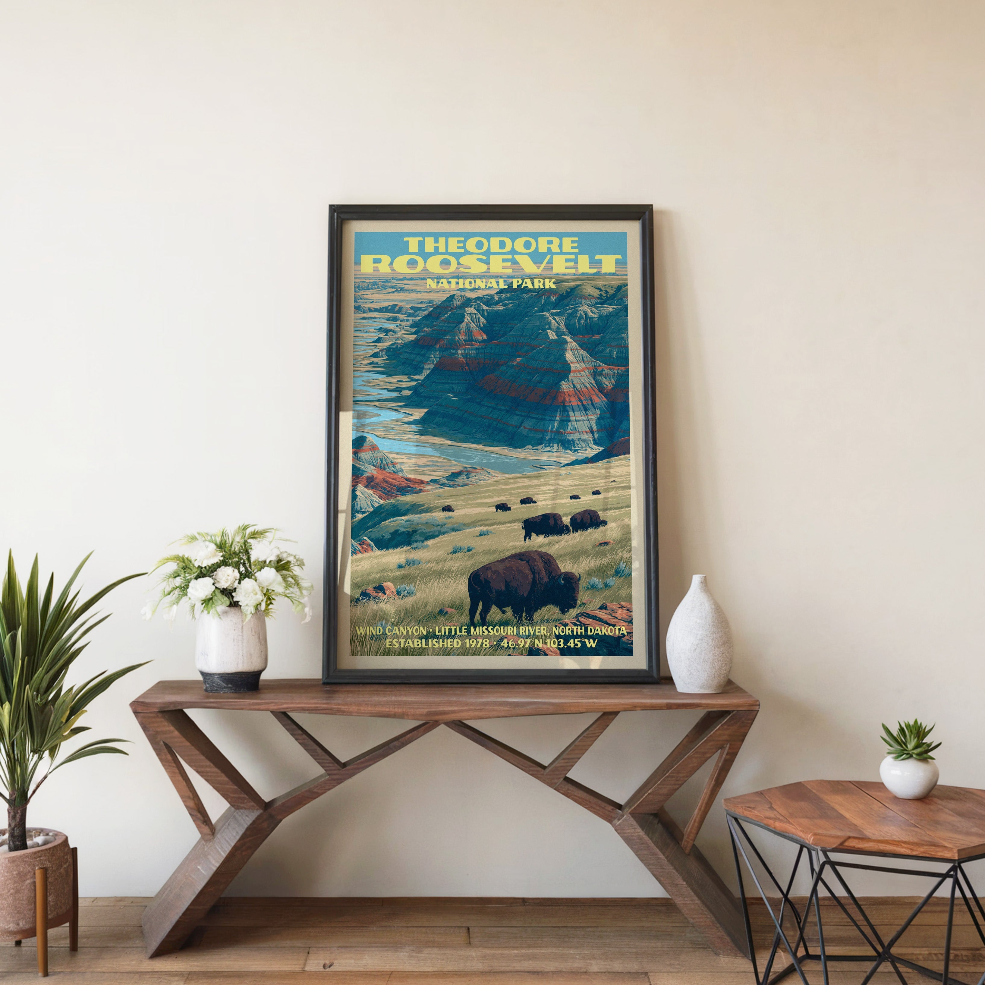 Wind Canyon bison wall art in black, leaning on a walnut console with white anemones and a small vase