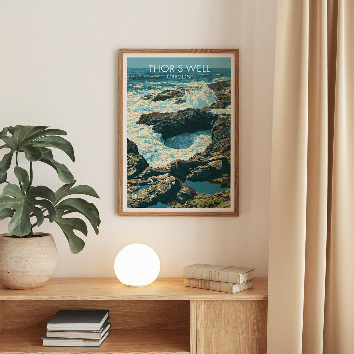 Oak-framed Cape Perpetua surf print on a beige wall above an oak console with a monstera and globe lamp