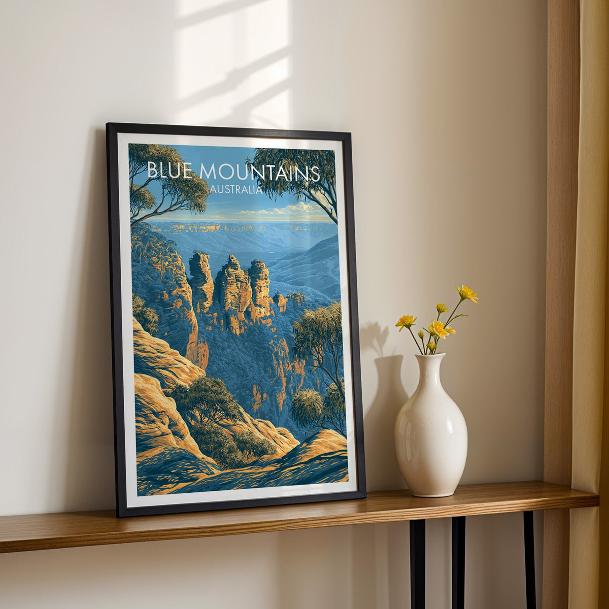 Sandstone pillars print in a black frame on a wood shelf with yellow daisies on a sunlit cream wall