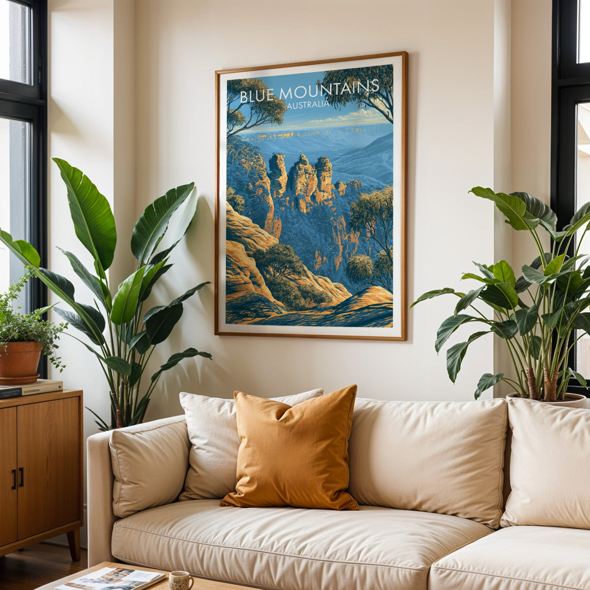 Blue Mountains travel poster in an oak frame above a cream sofa with a burnt-orange cushion